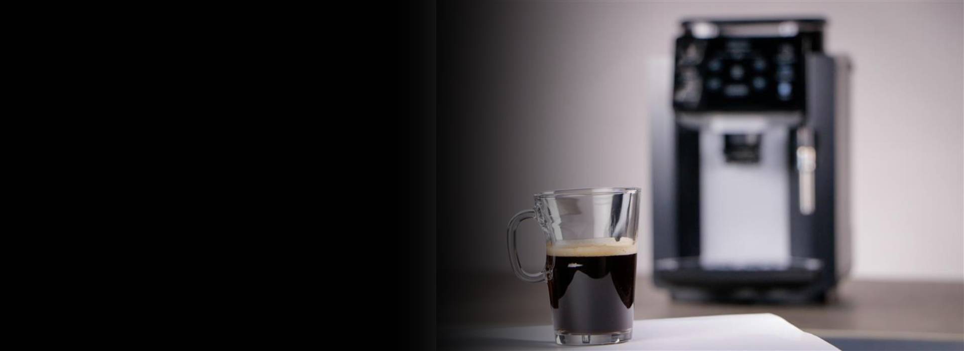Photo d'ambiance, avec une tasse de café au premier plan et une cafetière en arrière plan floutée, sur la droite.